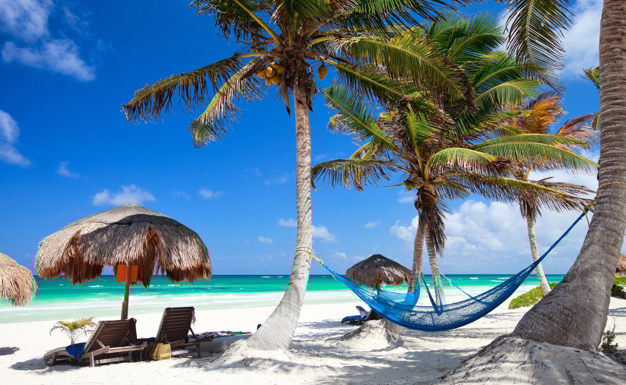 Loungers and a hammock on a sandy beach in Tulum