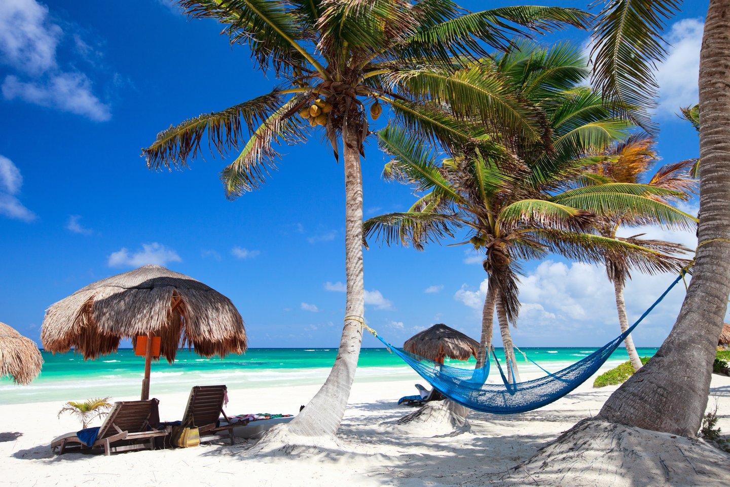 Loungers and a hammock on a sandy beach in Tulum