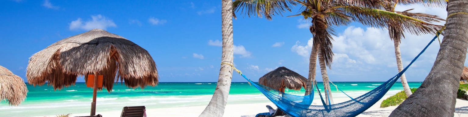 Loungers and a hammock on a sandy beach in Tulum