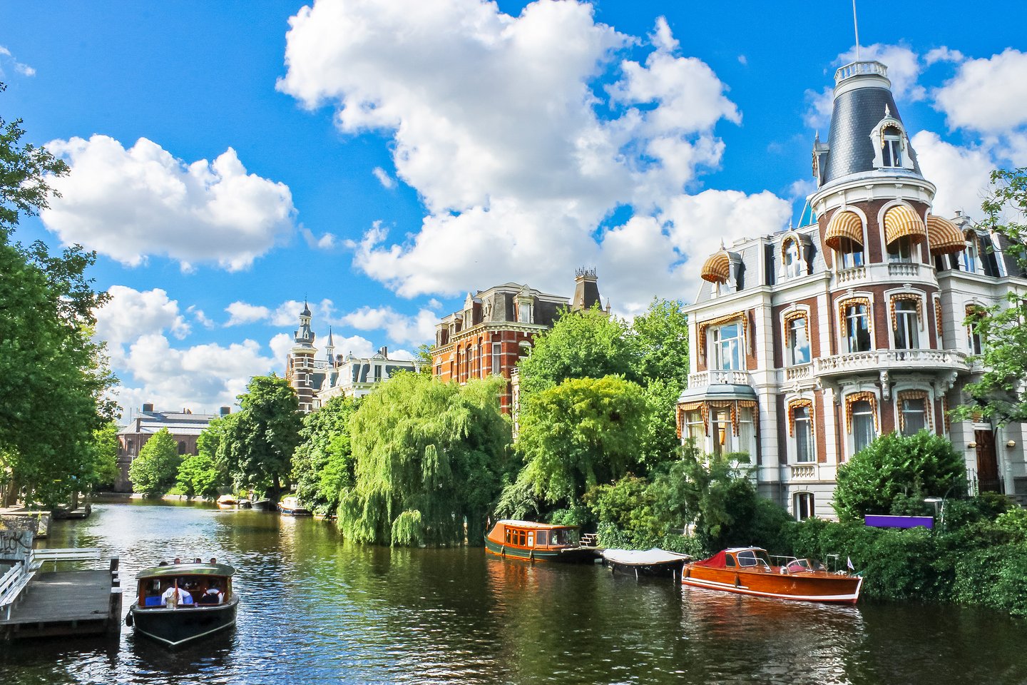 A canal in Amsterdam lined with trees and large houses