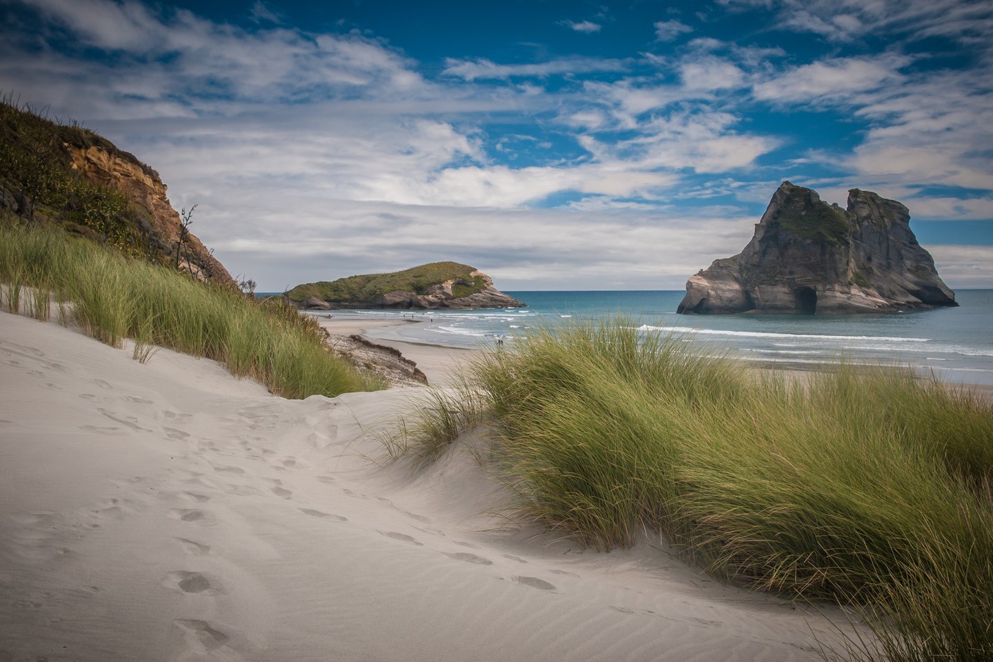 Footprints between along the sand dunes with Wharariki Beach in the distance