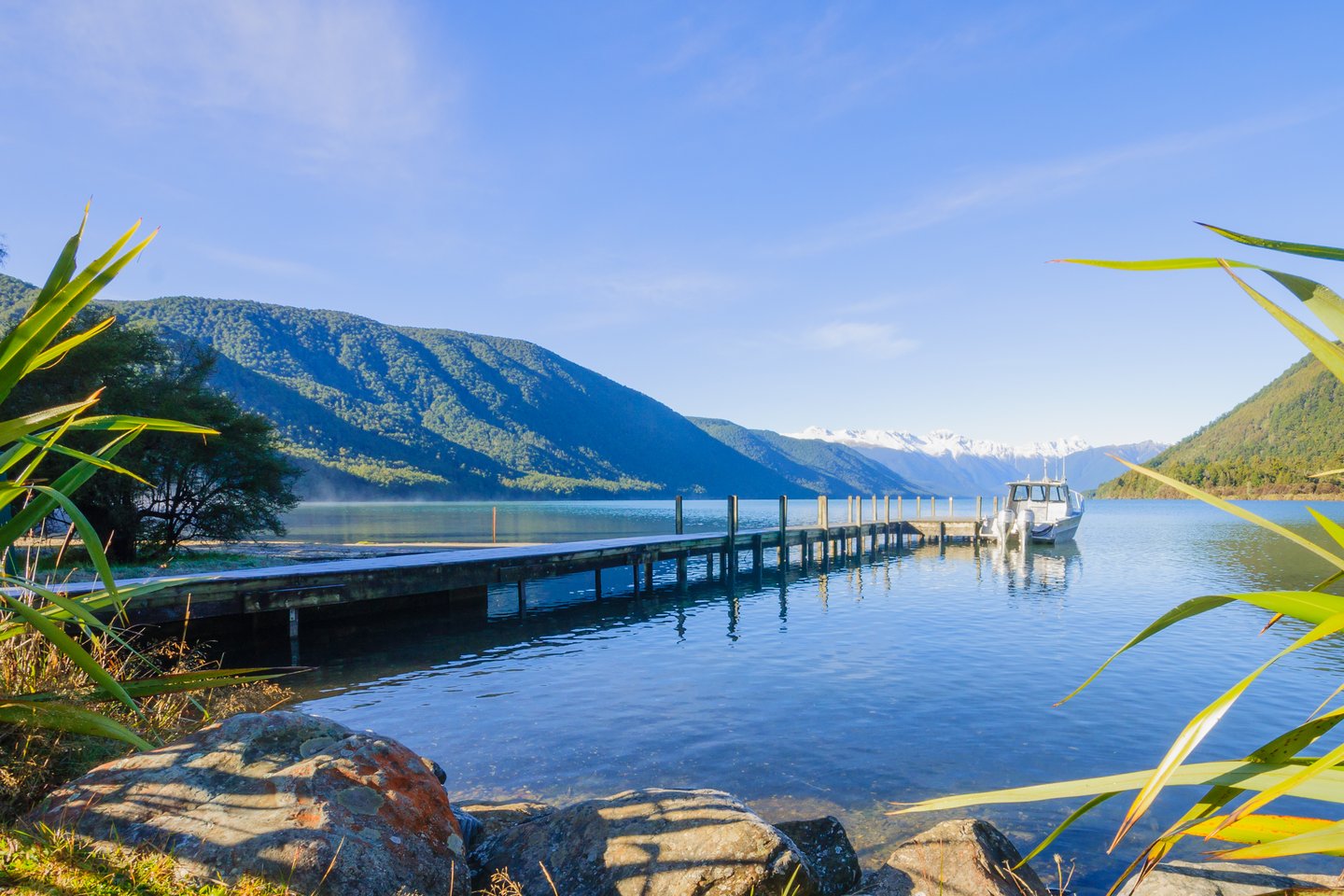 A boat moored at the wharf in Nelson Lakes National Park, New Zealand with mountains in the background