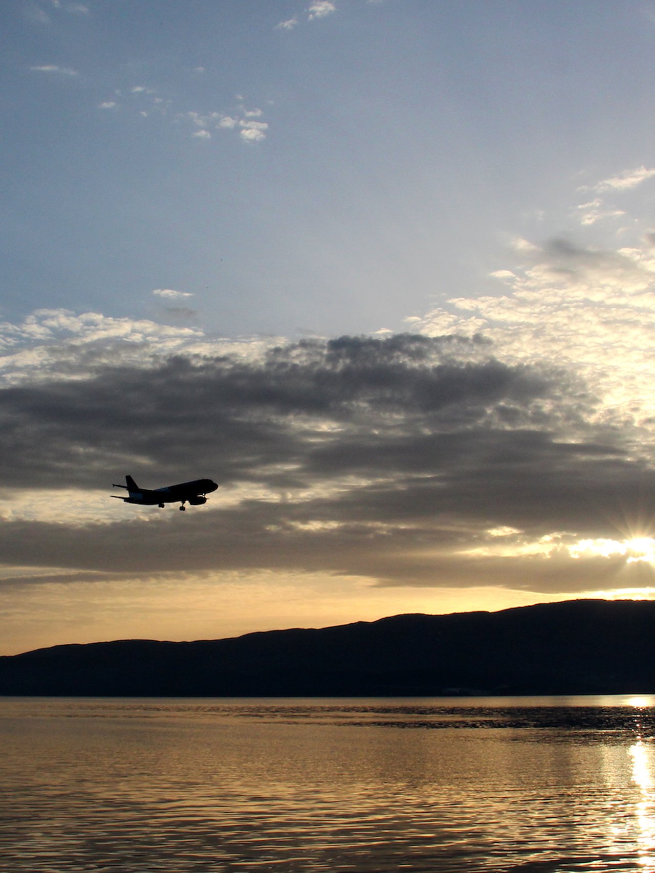 A plane flying above Lake Ohrid at sunset
