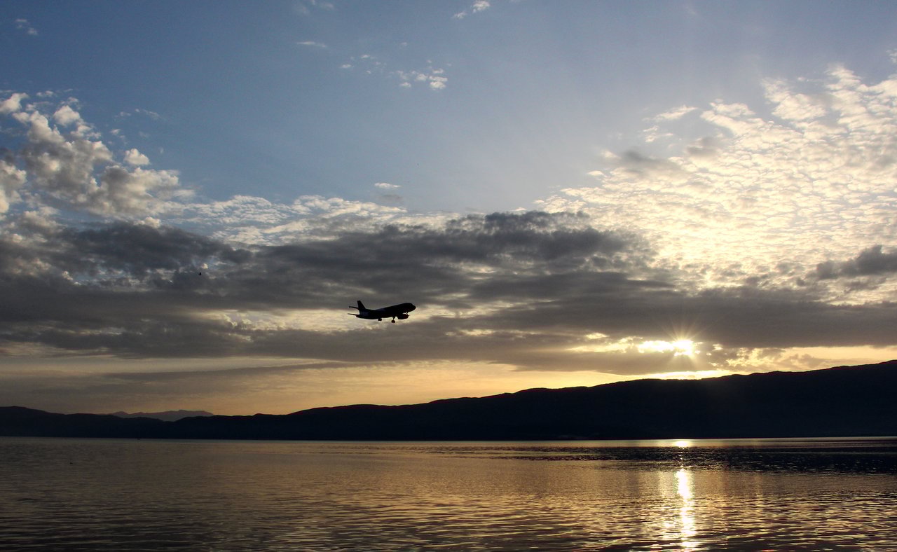A plane flying above Lake Ohrid at sunset