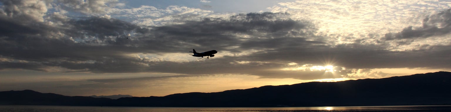A plane flying above Lake Ohrid at sunset