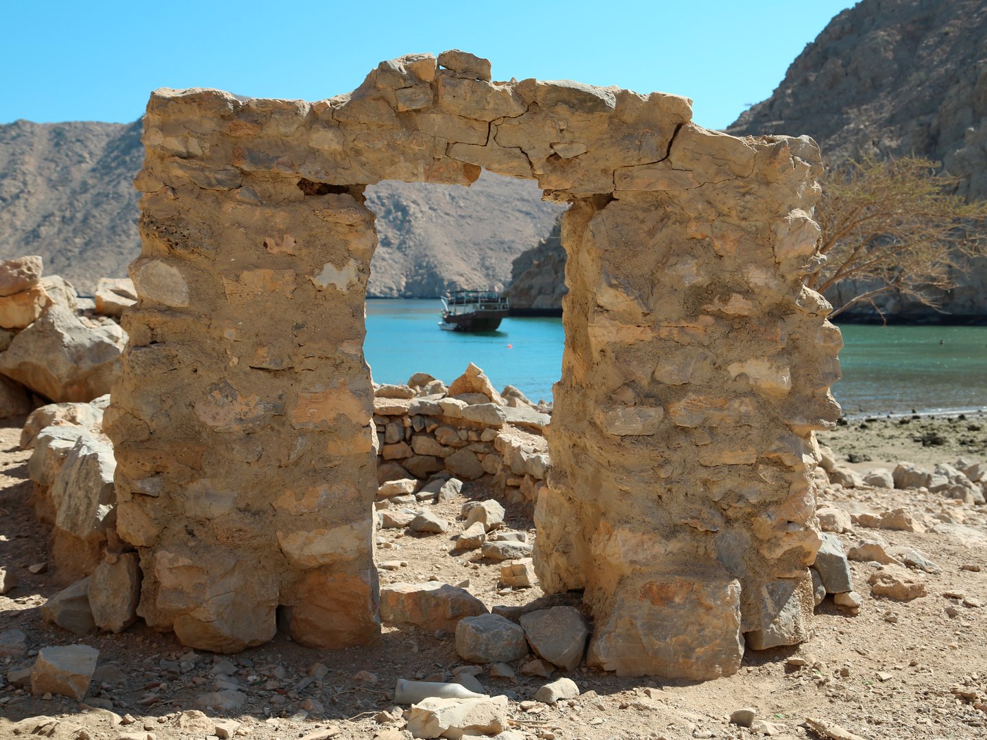 A boat framed by ruins in the ancient village of Haffa in Musandam, Oman