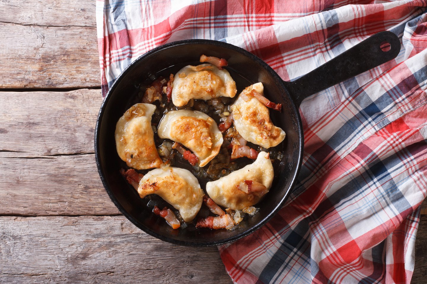 Pierogi fried with bacon bits in a pan