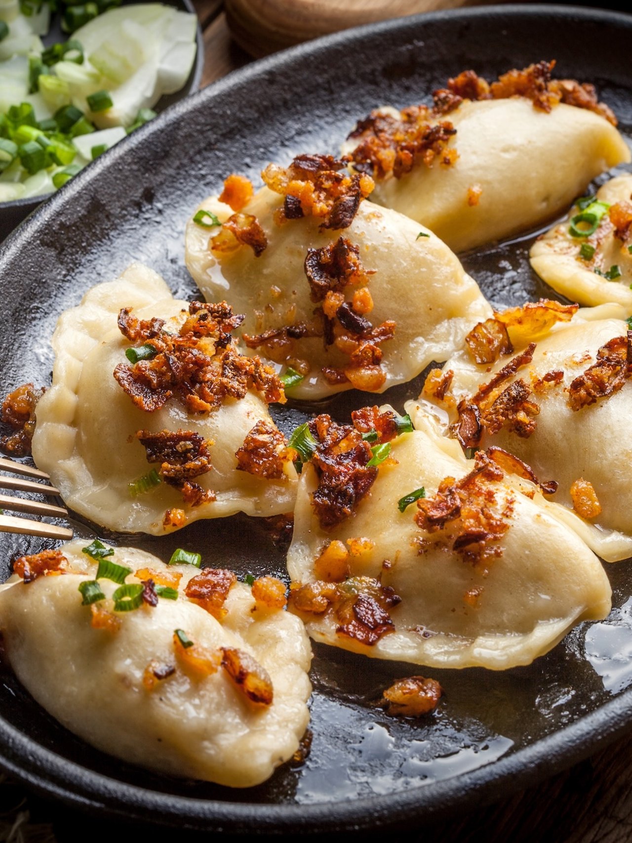 Pierogi, or Polish dumplings, filled with meat and topped with onion and bacon bits