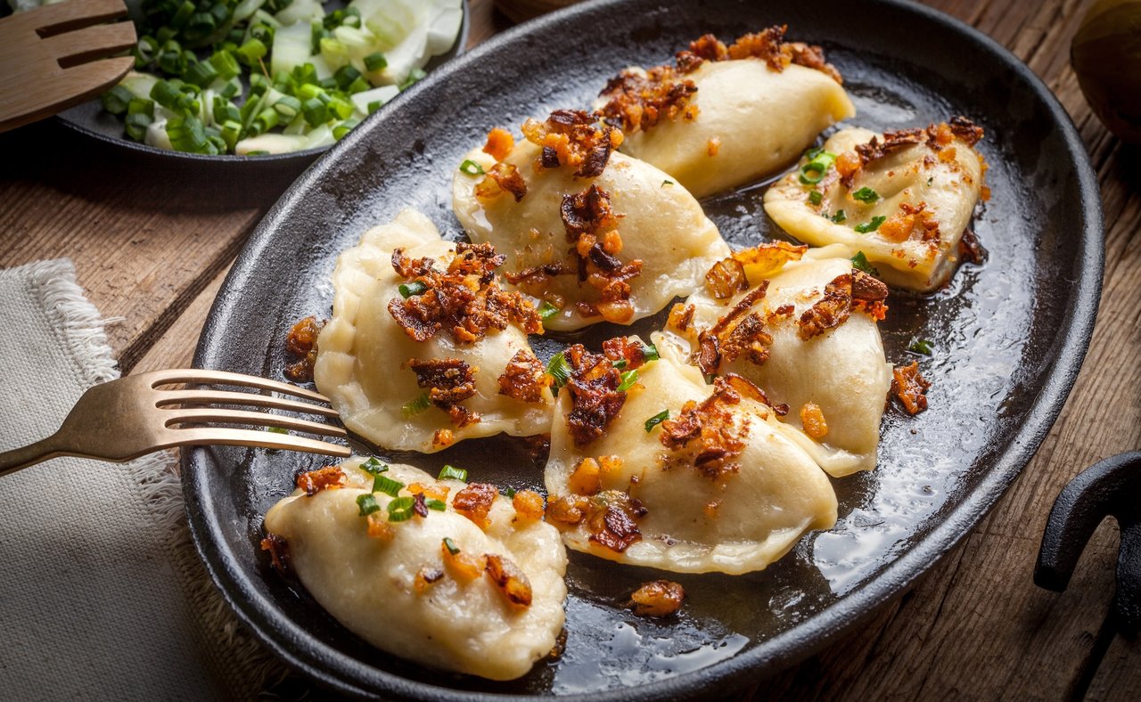 Pierogi, or Polish dumplings, filled with meat and topped with onion and bacon bits