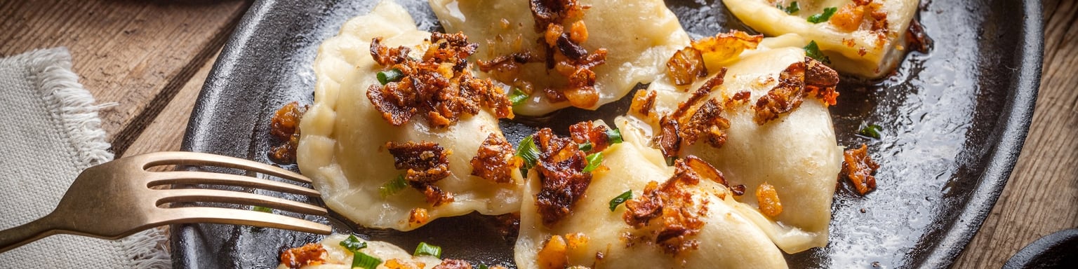 Pierogi, or Polish dumplings, filled with meat and topped with onion and bacon bits
