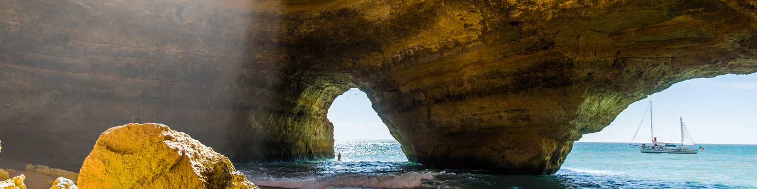 Light streaming into Benagil Cave with a boat docked outside.