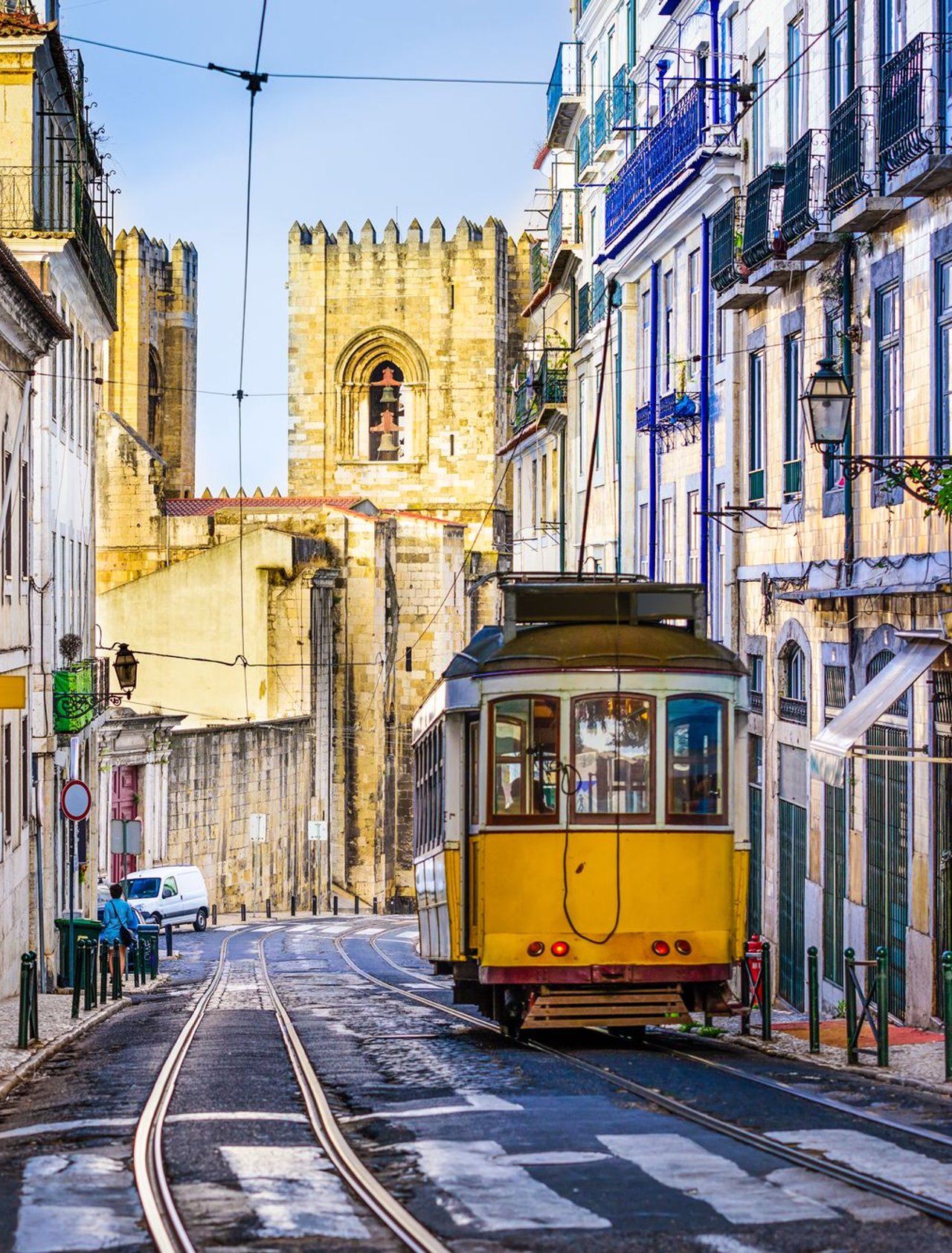 An iconic, yellow tram surrounded by historic buildings in Lisbon, Portugal.