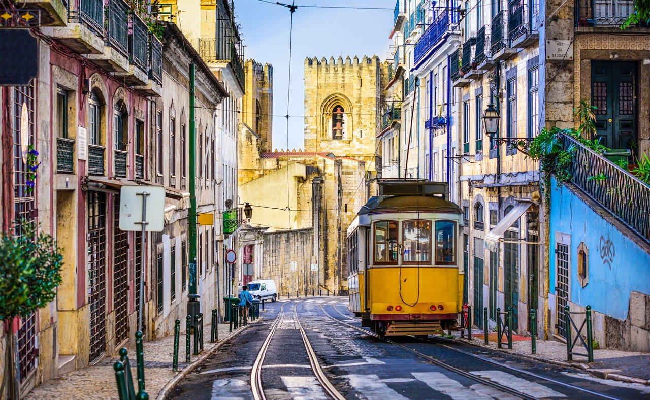 An iconic, yellow tram surrounded by historic buildings in Lisbon, Portugal.
