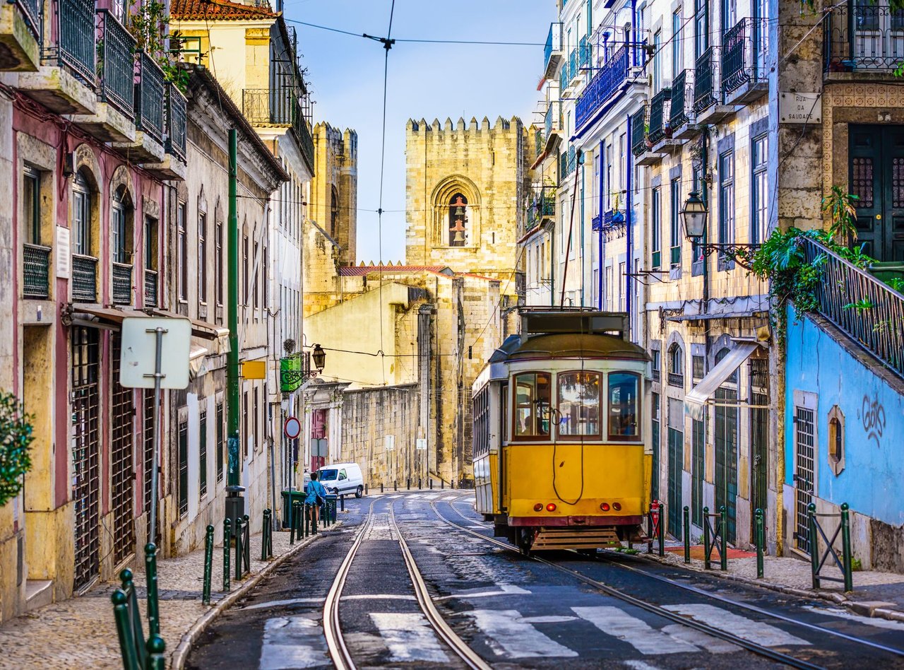 An iconic, yellow tram surrounded by historic buildings in Lisbon, Portugal.
