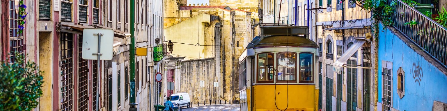 An iconic, yellow tram surrounded by historic buildings in Lisbon, Portugal.