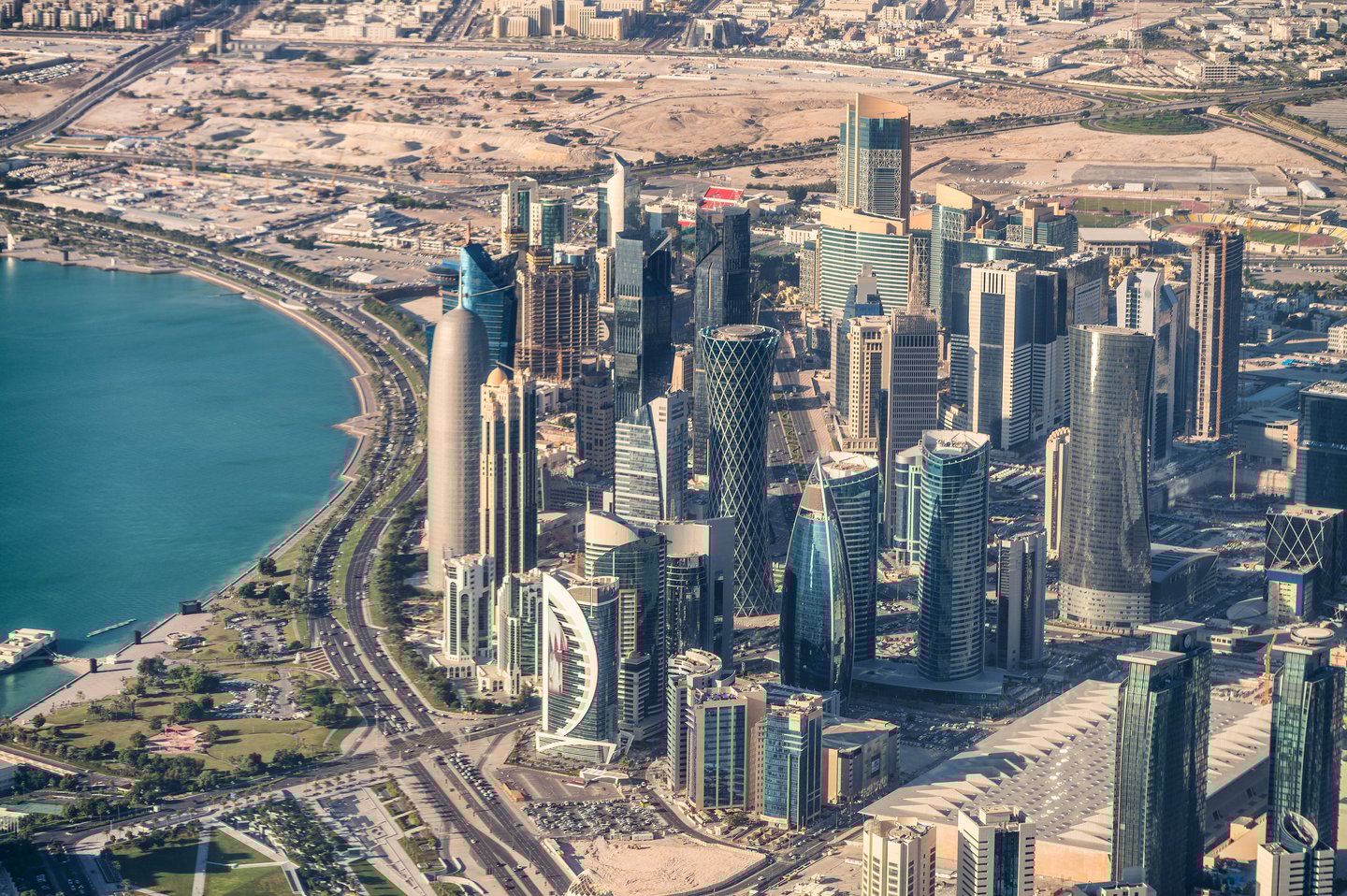 An aerial view of Doha, Qatar, showing skyscrapers, deserts and a glimpse of the sea