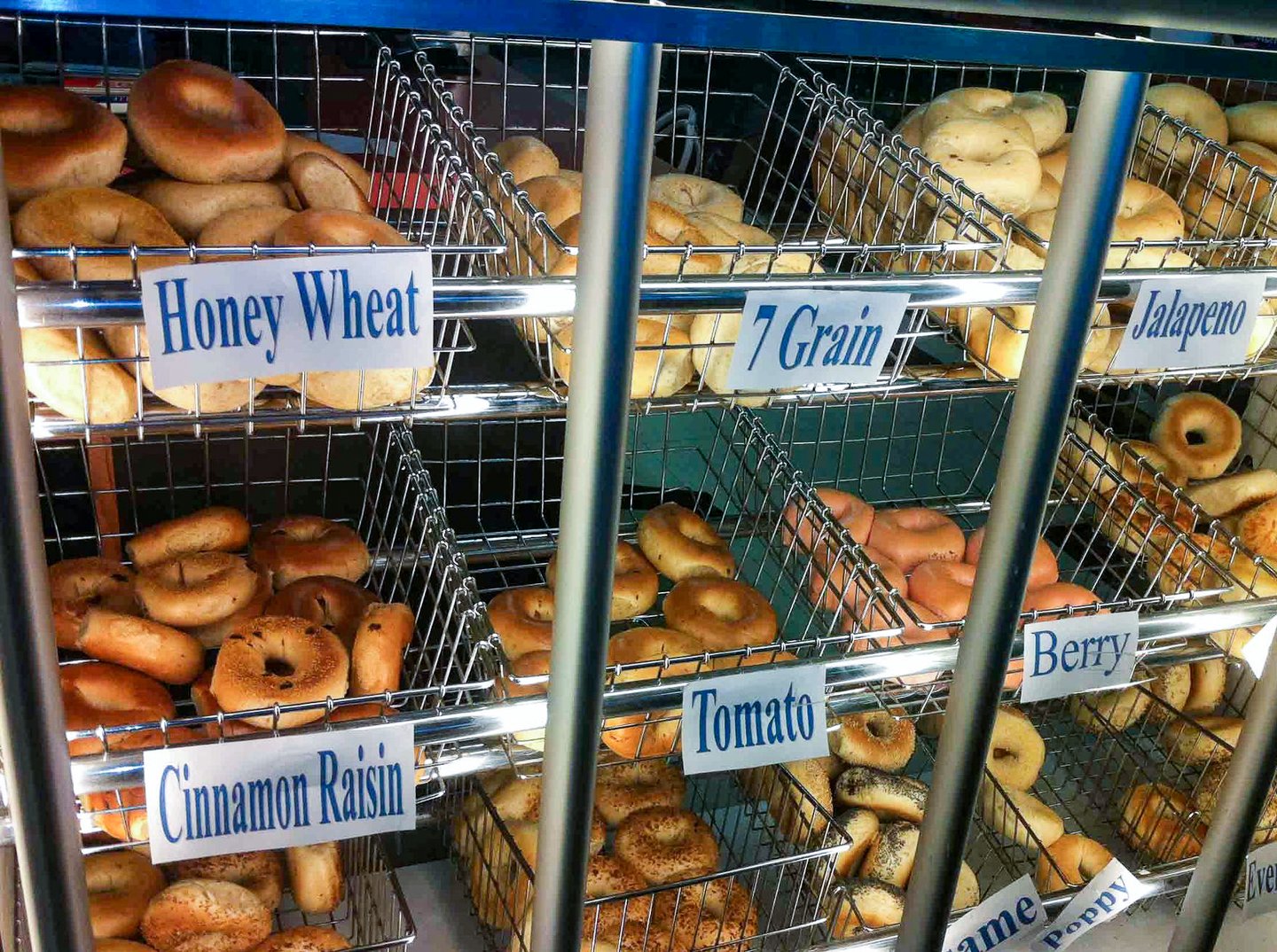 Different flavoured bagels in stainless steels baskets on a rack