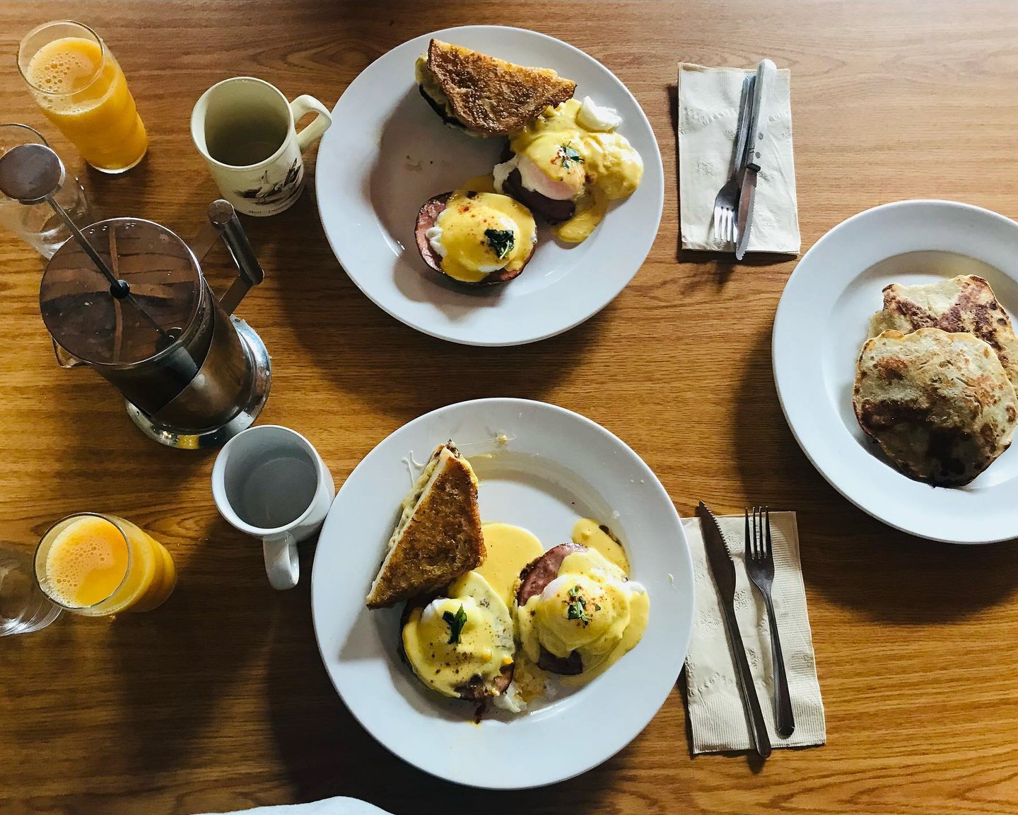 Breakfast with eggs benedict, toast, orange juice and coffee on a table