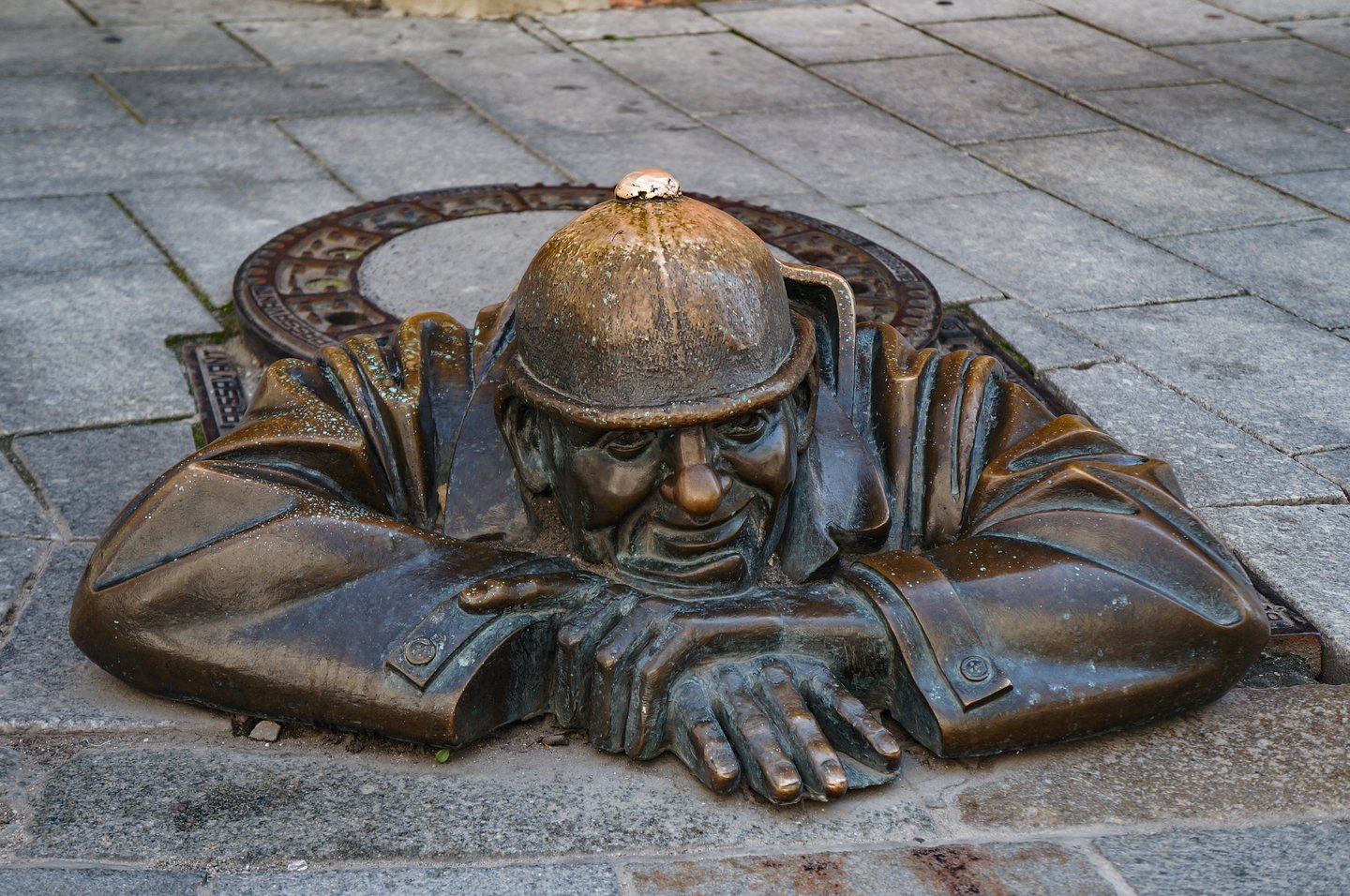 The Čumil, a bronze statue on a sewer worker resting on top of a manhole