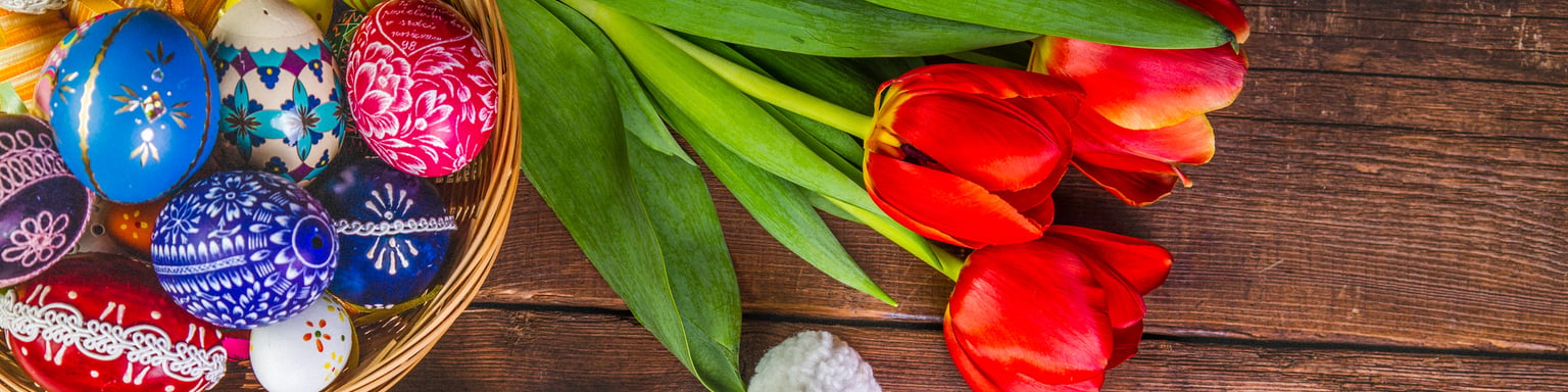 A basket of painted eggs with tulips and small, ornamental sheep
