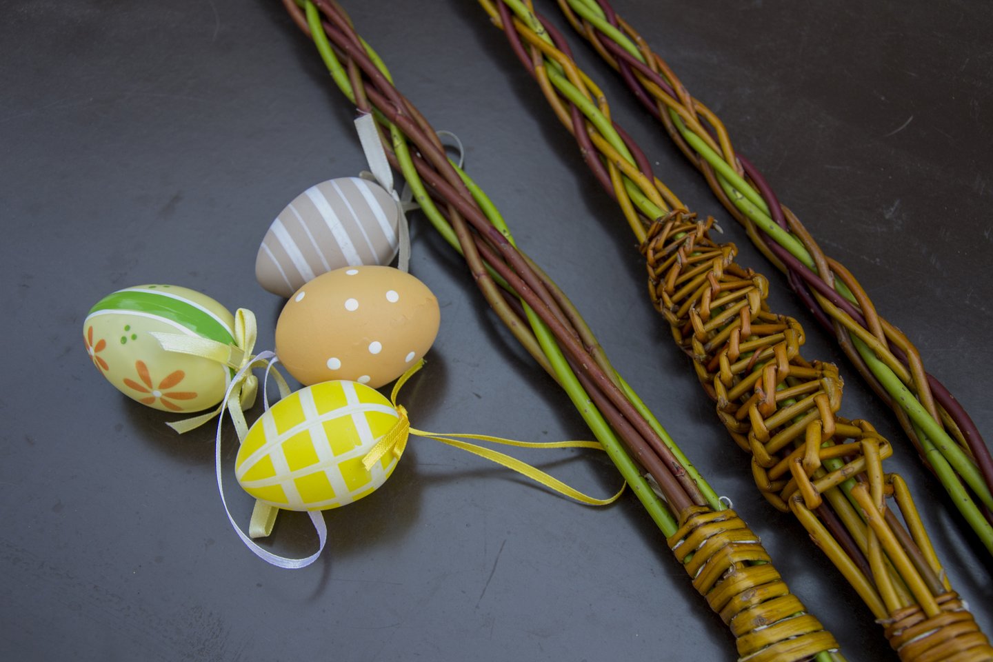 Colourful, painted eggs next to woven, willow whips