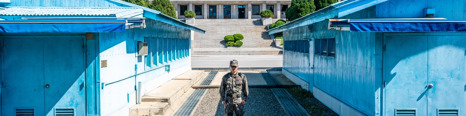 A soldier standing between the blue buildings at the Joint Security Area in Korea
