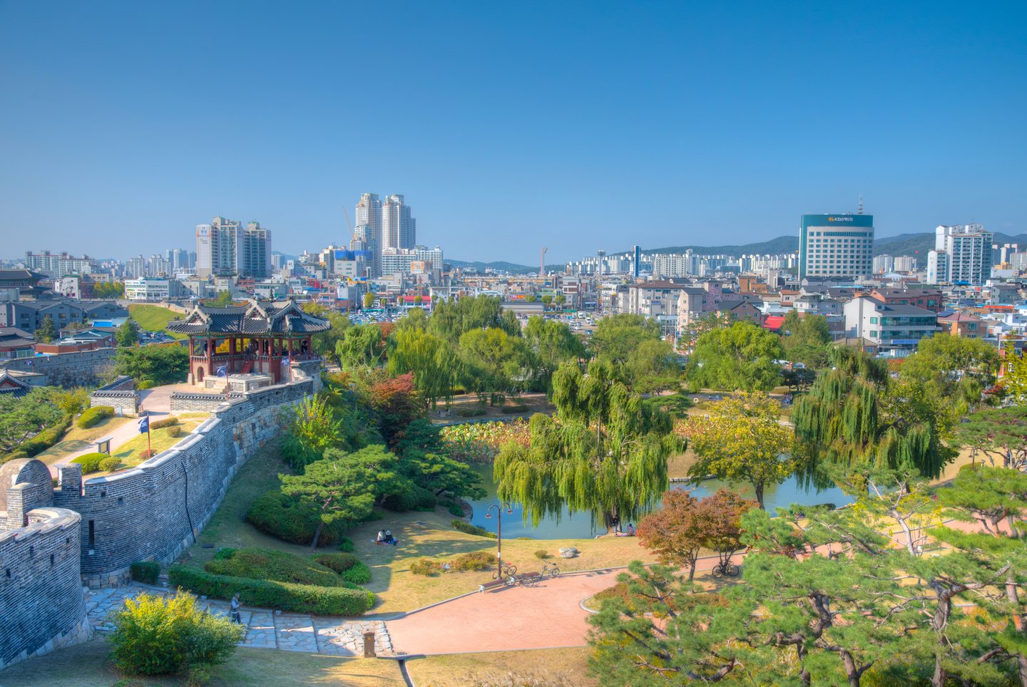 A view over Suwon, South Korea including a lake, the walls and the city in the distance.