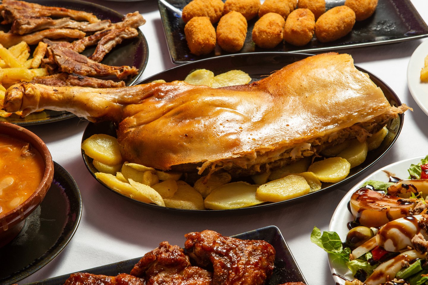 Cochinillo (roasted suckling pig) from Segovia surrounded by other dishes