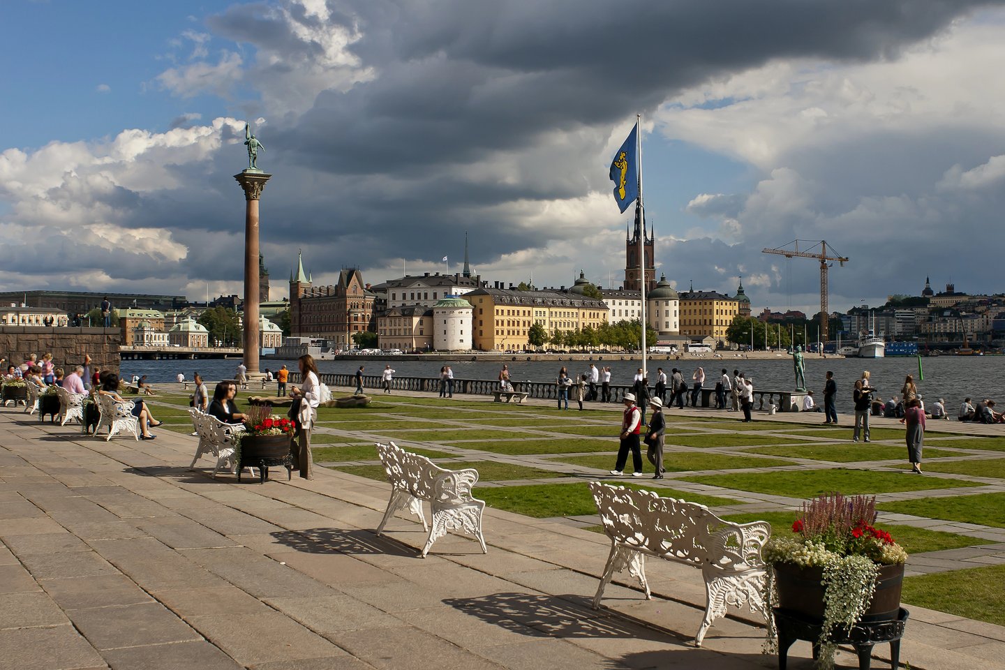 People sitting on benches outside a monument in Kungsholmen, Stockholm