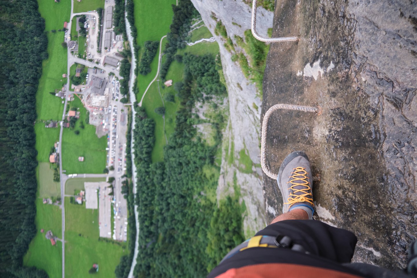 Stepping on a ferrata grip overlooking the valley in Switzerland.