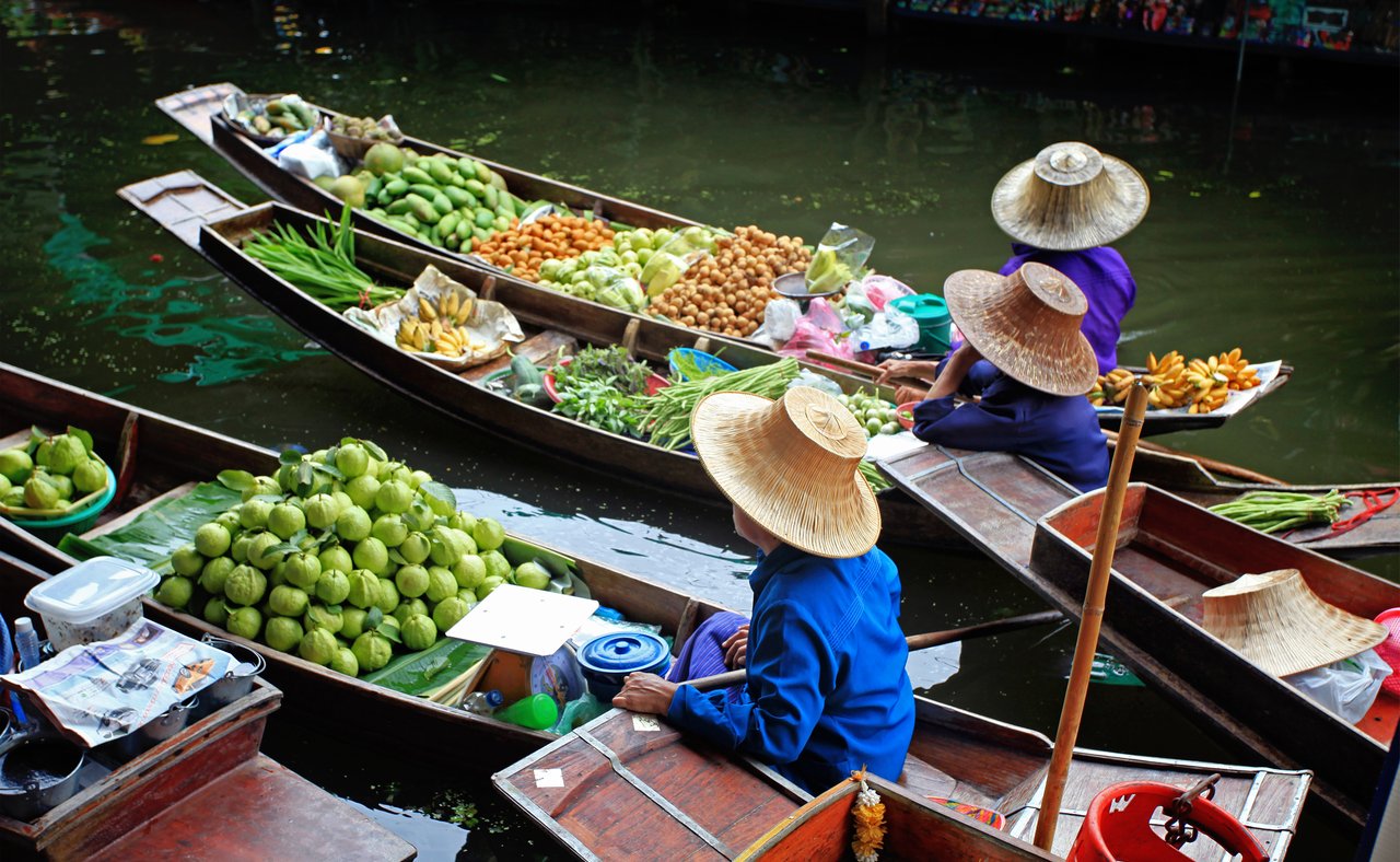 Vendors selling fruit and vegetables at a floating market in Thailand.