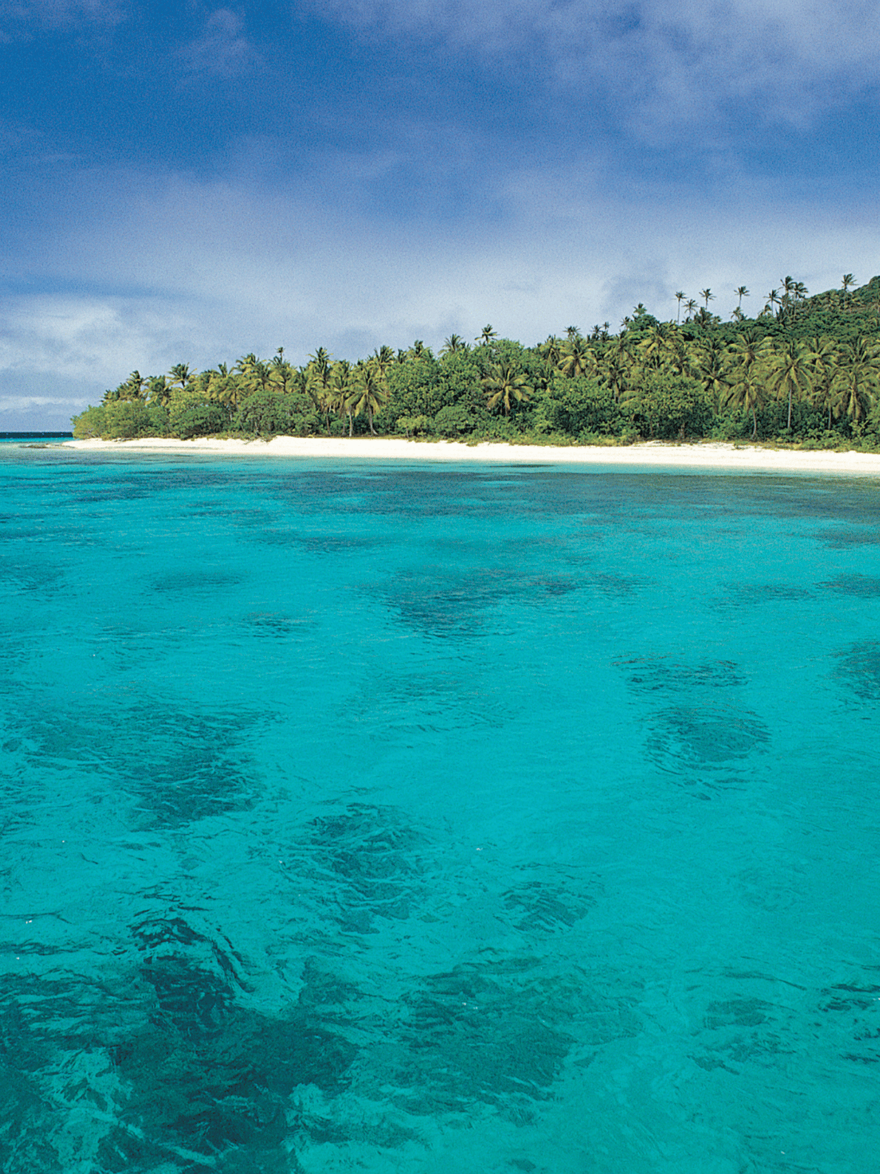 Clear, blue water with an island in the background on a sunny day