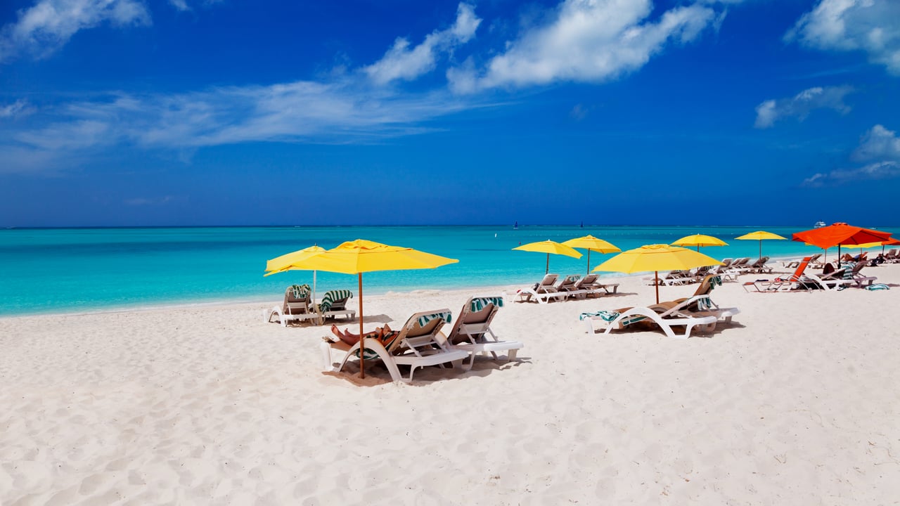 Colourful umbrellas and lounges on the white, sandy Grace Bay Beach in Turks and Caicos