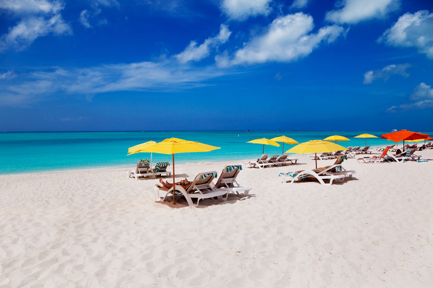 Colourful umbrellas and lounges on the white, sandy Grace Bay Beach in Turks and Caicos