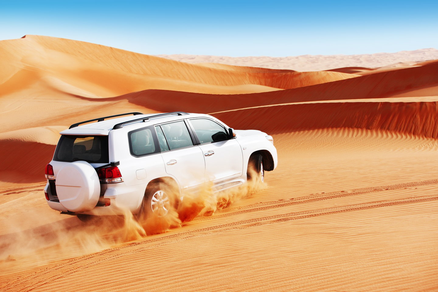 A 4x4 races up a sand dune in the Arabian desert