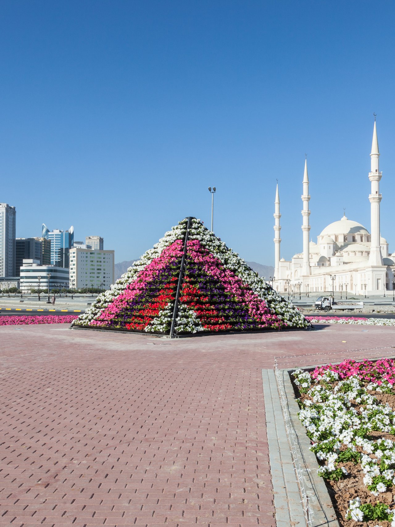 Fujairah Grand Mosque and cityscape with colourful flowers in the foreground