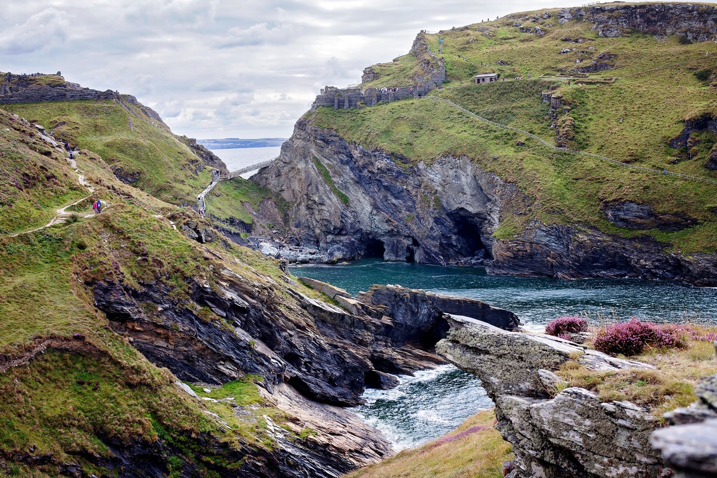 Blue sea, green hills and ancient walls in Tintagel Bay, Cornwall