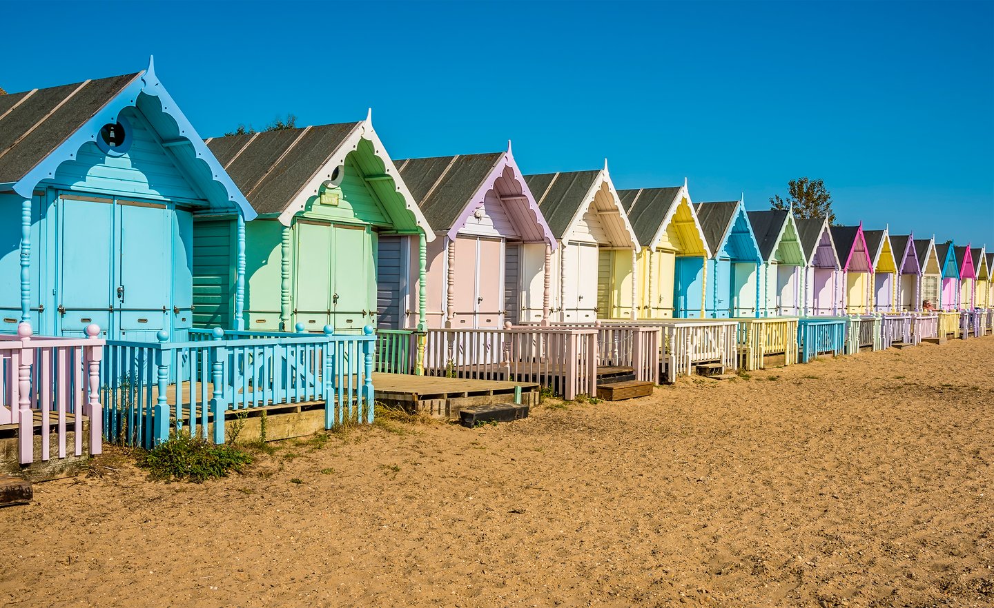 Brightly coloured beach huts on West Mersea beach, UK in the summertime