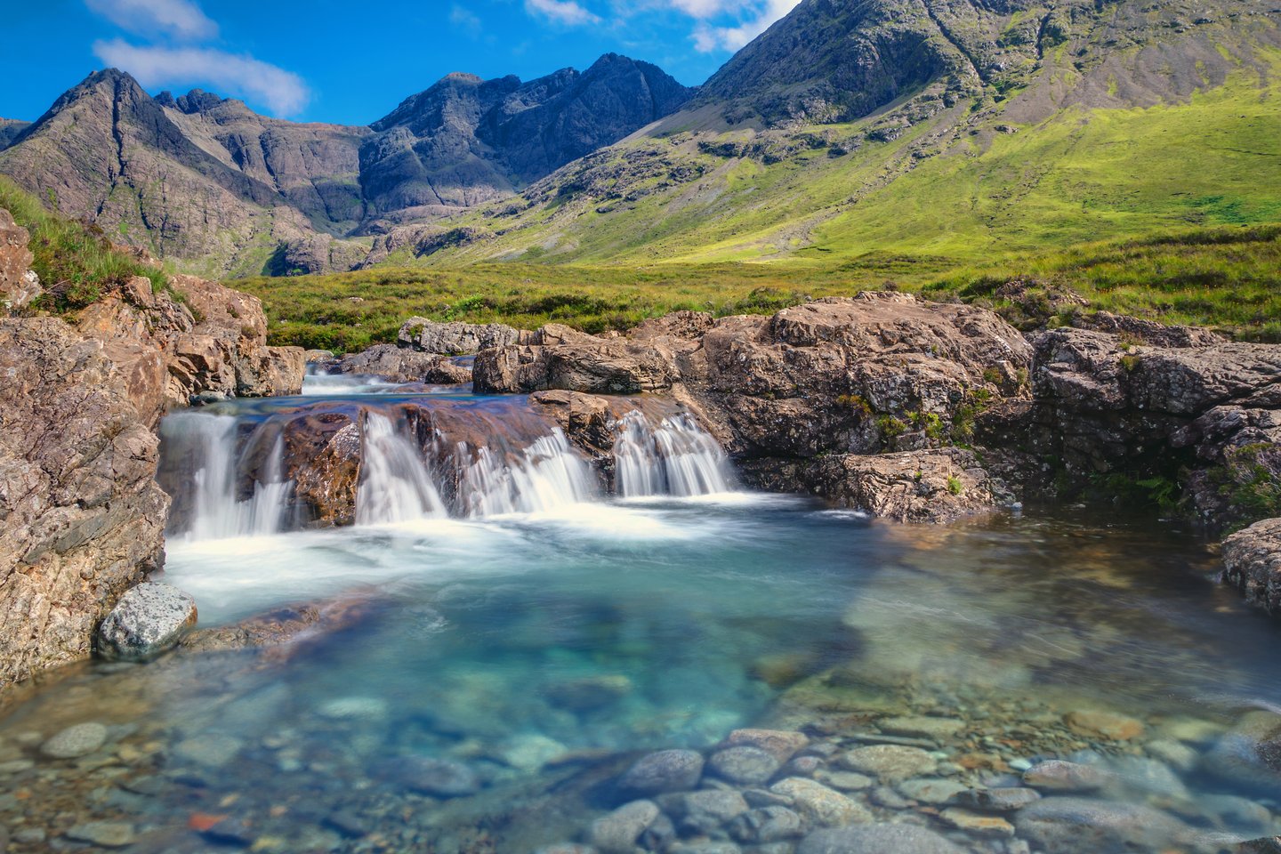 A small waterfall surrounded by mountains at the Fairy Pools in the Isle of Skye