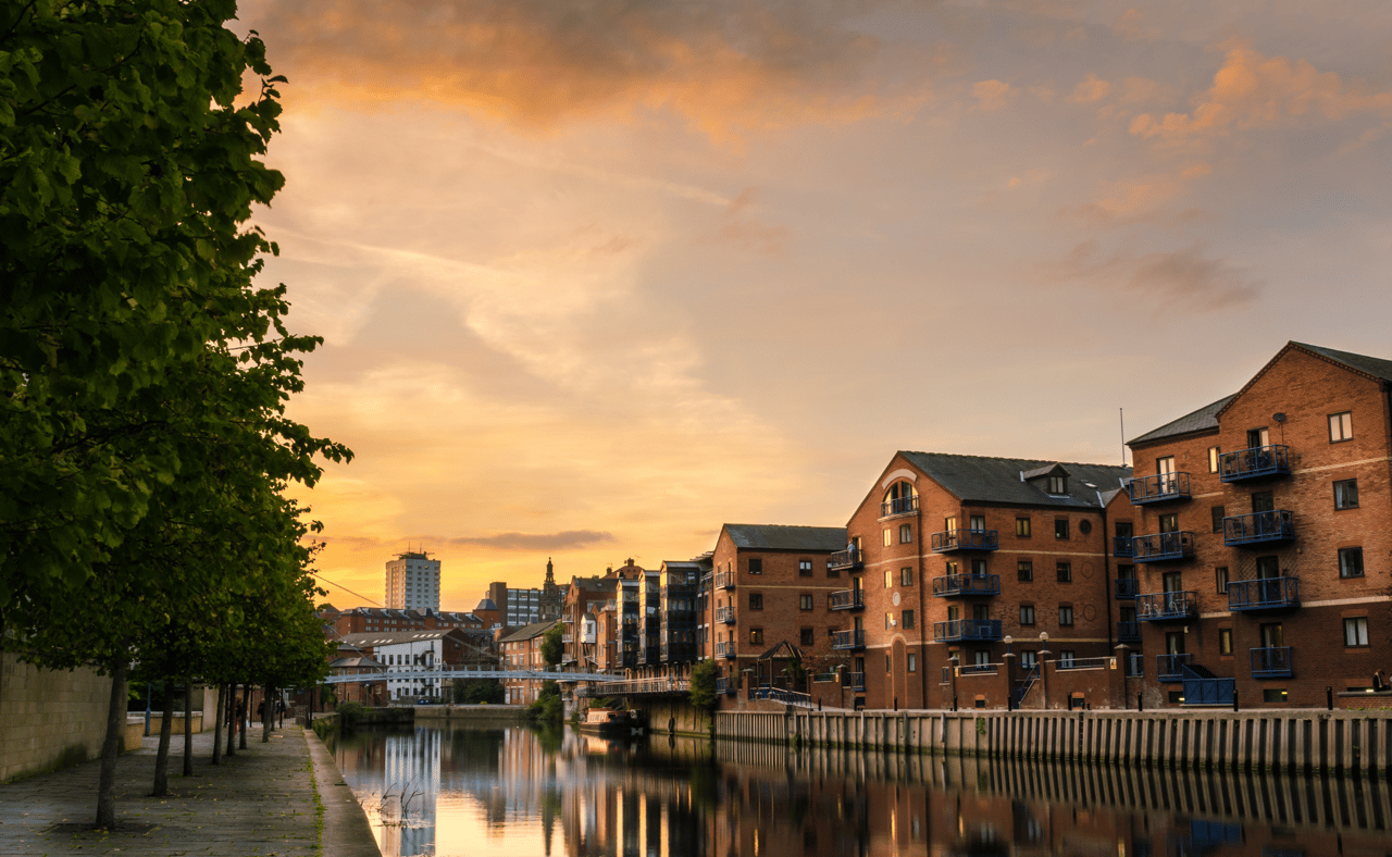 Redeveloped warehouses and modern bridge on the River Aire in Leeds at sunset