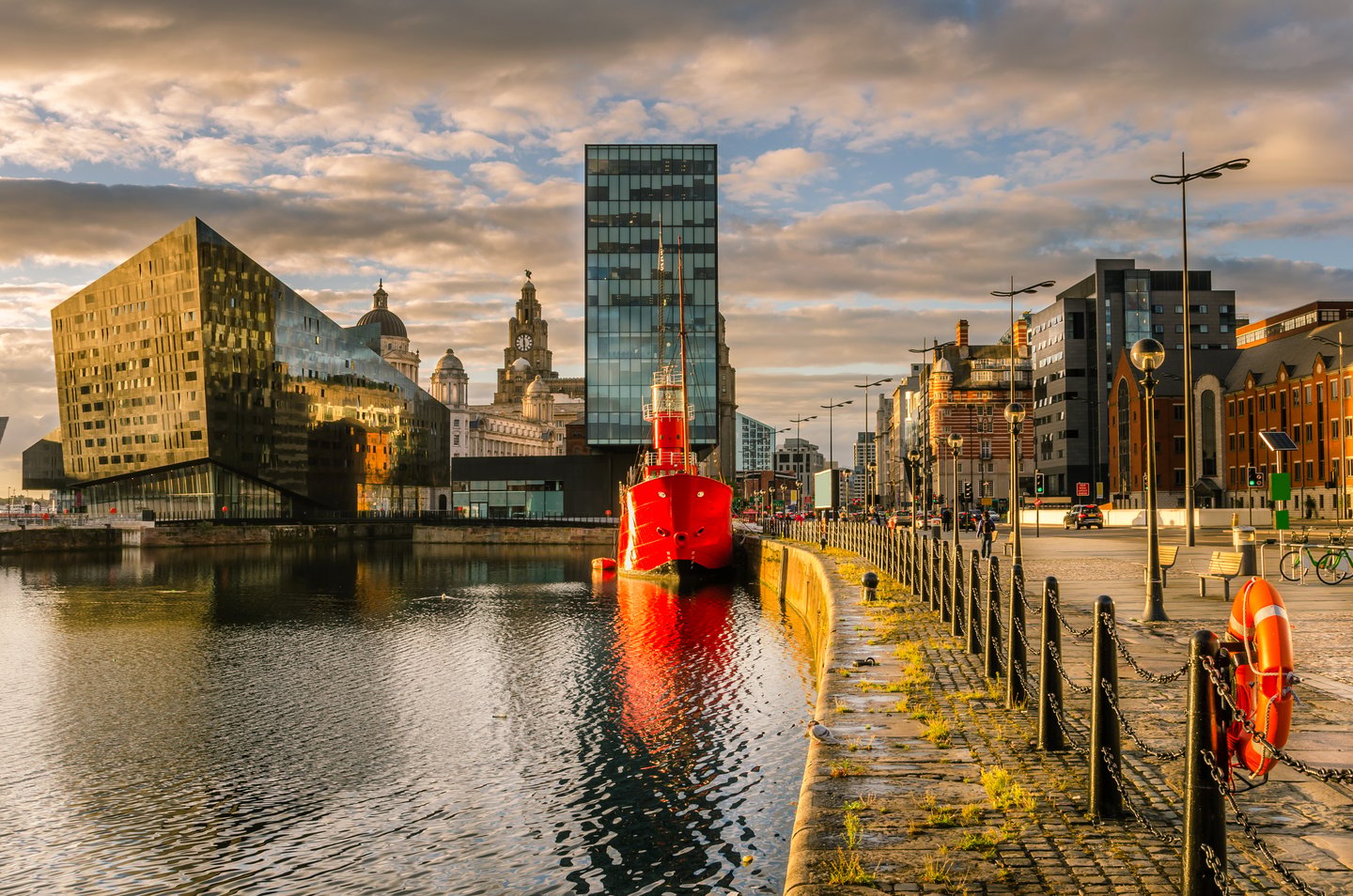 Sunset over Liverpool waterfront with a red boat in the water
