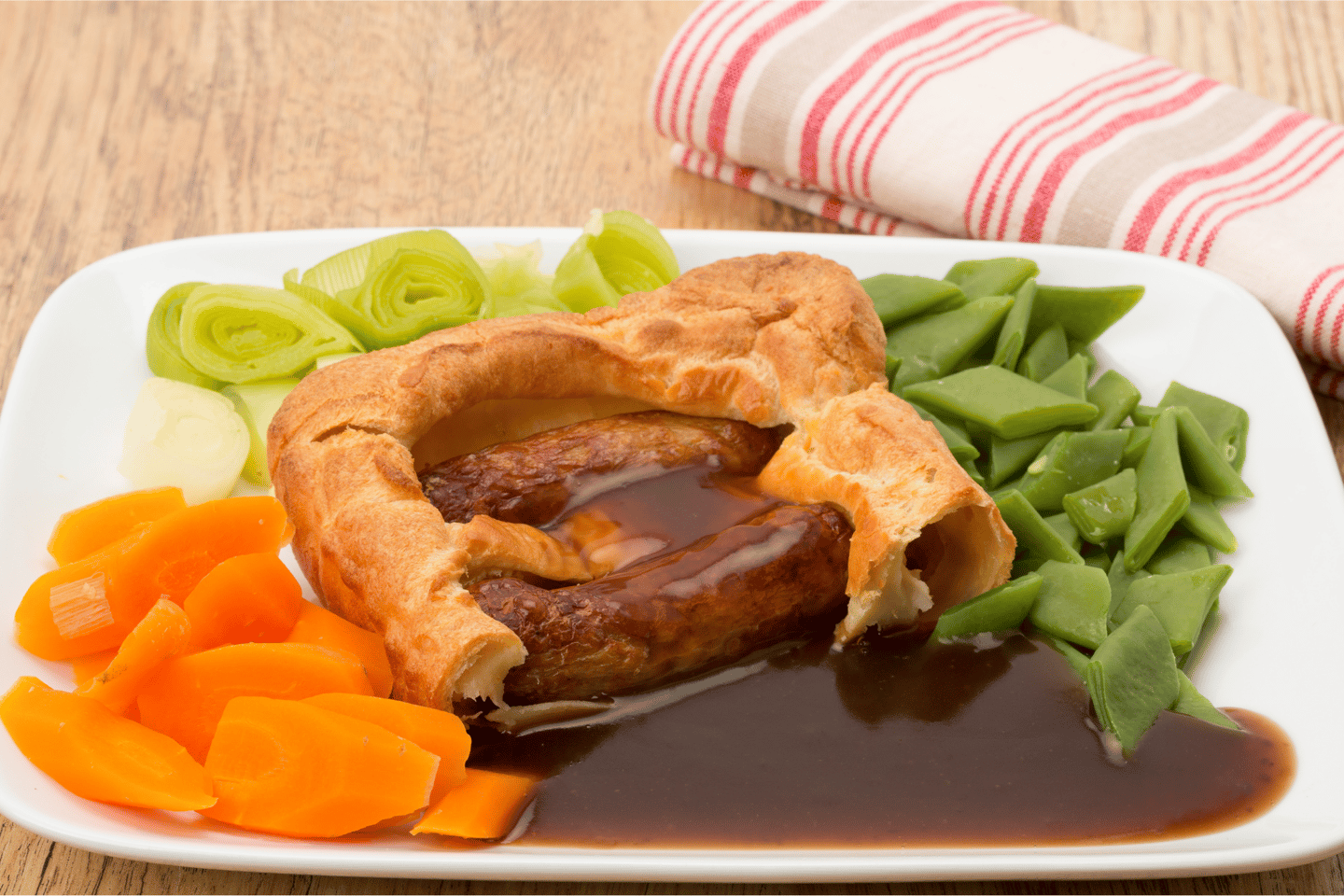 Classic British dinner of Toad in the Hole with vegetables and thick gravy