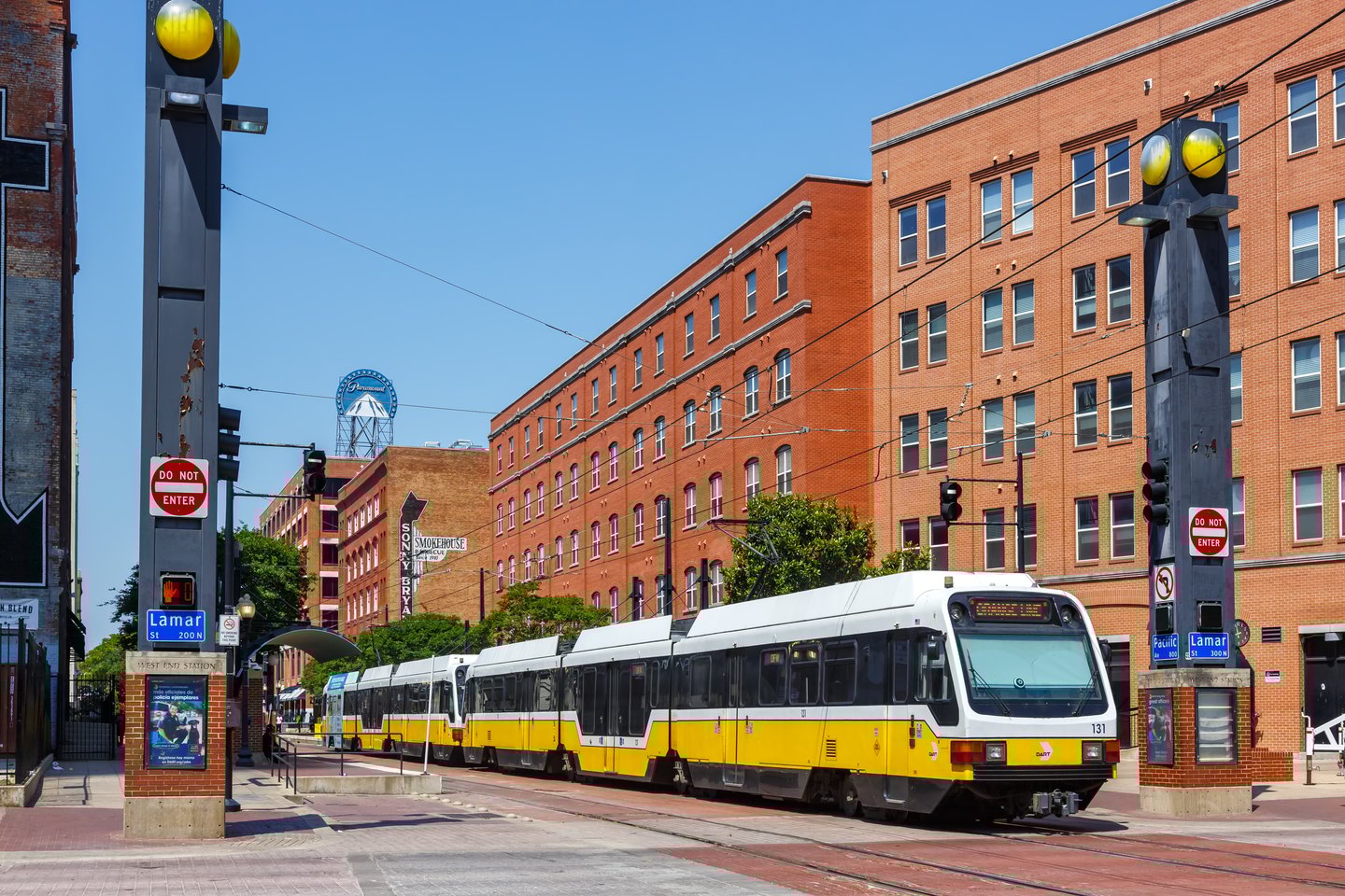 A yellow and white DART train in Dallas, Texas, on a sunny day
