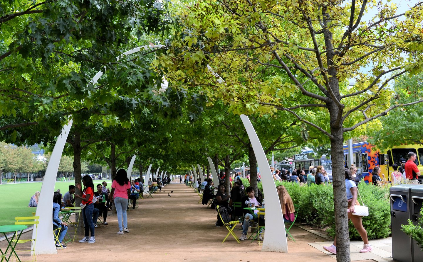 Food trucks and tables under trees at Klyde Warren Park in Dallas.