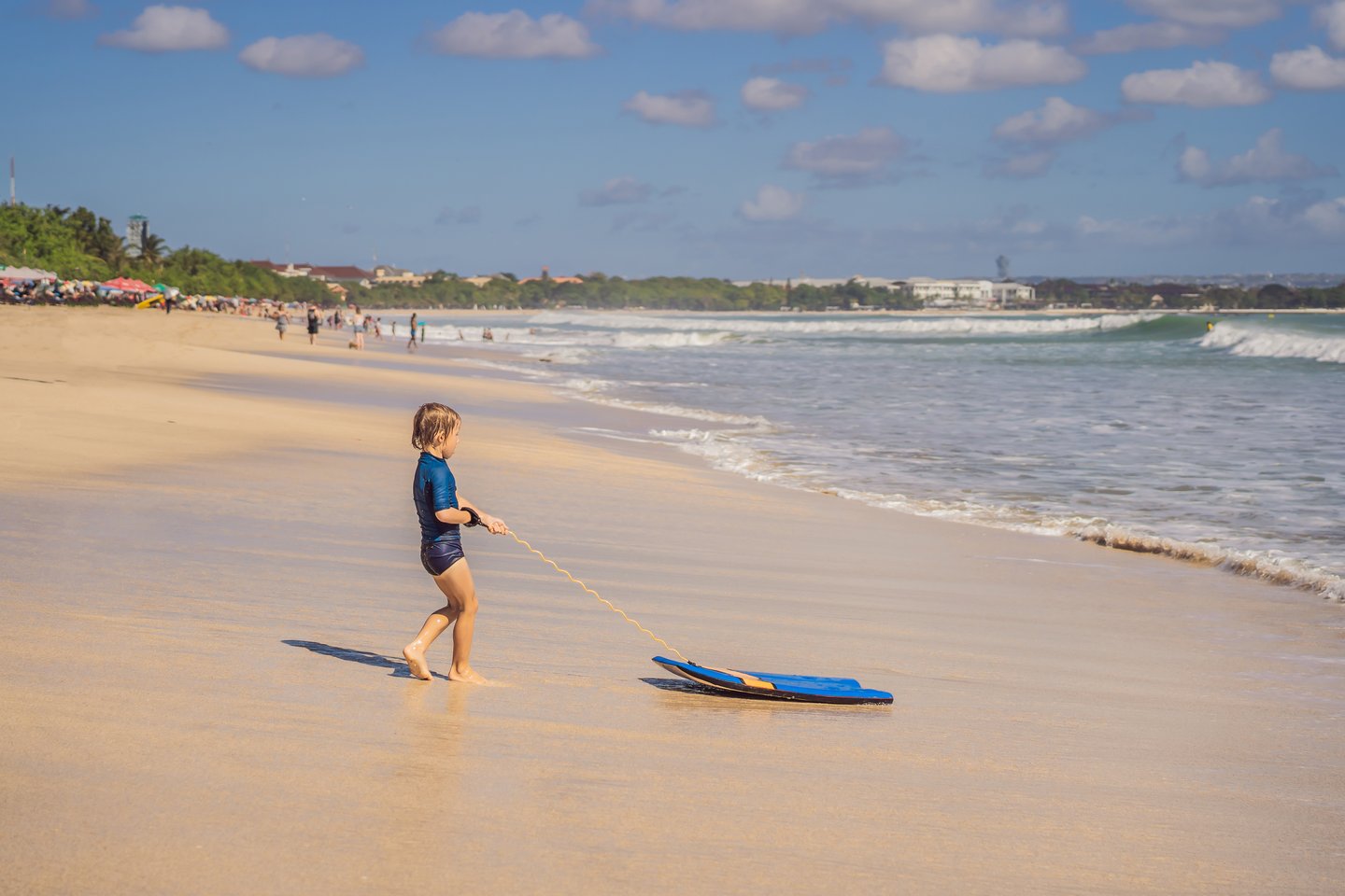 A young child with a boogie board at the beach in Maui