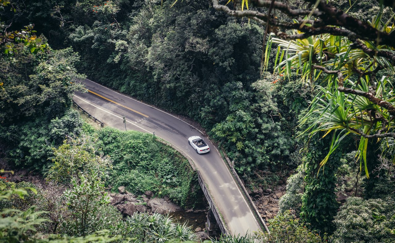 People drive a convertible car on scenic tropical road to Hana in Maui, Hawaii