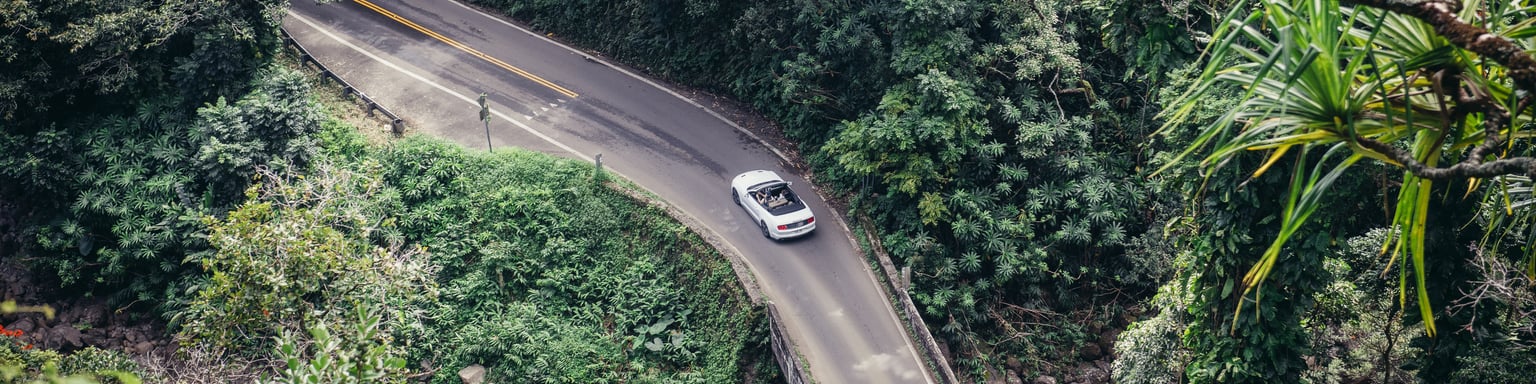 People drive a convertible car on scenic tropical road to Hana in Maui, Hawaii