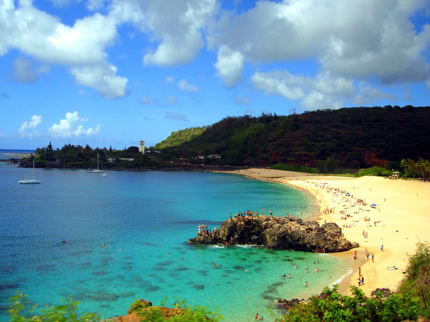 People swimming and sunbathing on North Shore Beach in Oahu, Hawaii on a sunny day