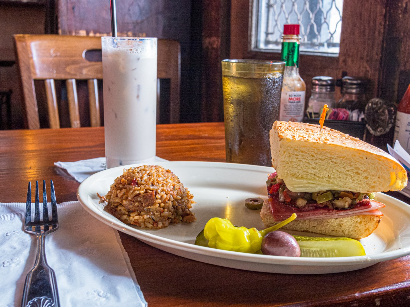 Muffeletta and jambalaya on a white plate with a bourbon milk punch at the historic Napoleon House in the French Quarter