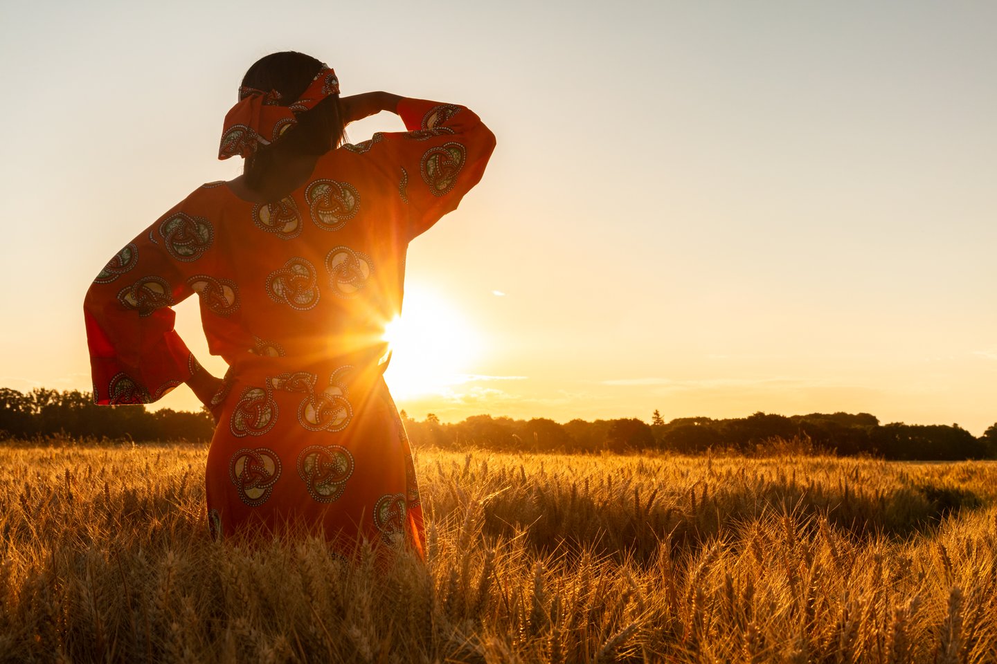 A women in a traditional dress in a field at sunset